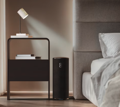 Eight Sleep Pod base unit on the floor beside a black bedside table with mushroom lamp and styled bed