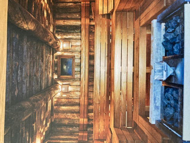 Wood-paneled sauna interior with rocks and warm interior light