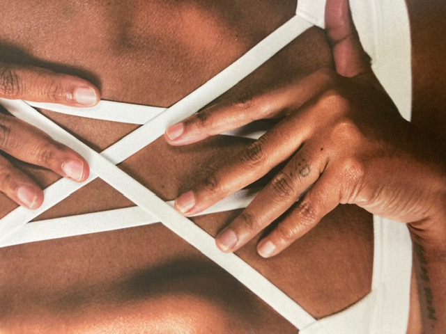 Close-up of a practitioner's hands and white sports-bra straps on a client's back
